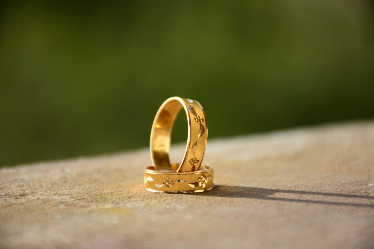 Close-up of two decorative gold wedding rings casting shadows on a warm surface.